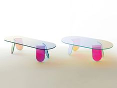 two glass tables sitting next to each other on top of a white floor with pink and blue accents