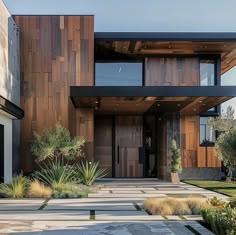 a modern house with wood siding and stone walkway leading up to the front door area