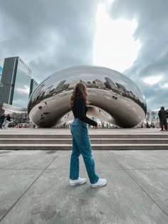 a woman walking in front of a large sculpture