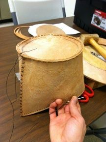 a person is working on some kind of leather bag with scissors and pliers next to it