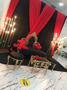 an elaborately decorated room with red and black drapes, gold chairs and candles