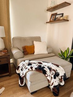 a living room with a couch, chair and cow print blanket