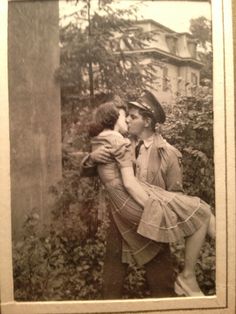 an old black and white photo of a man kissing a woman