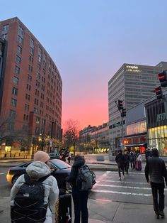 people are walking down the street at sunset