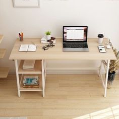 a laptop computer sitting on top of a wooden desk next to a plant and books