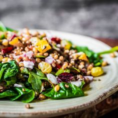 a white plate topped with salad on top of a wooden table