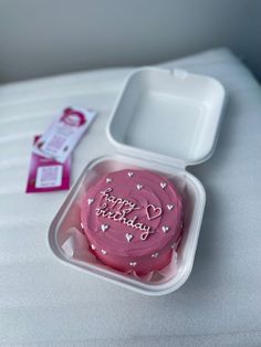 a pink birthday cake in a plastic container