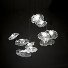 several glass bowls suspended from strings in the dark room with light coming through them,