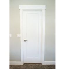 an empty room with a white door and carpet