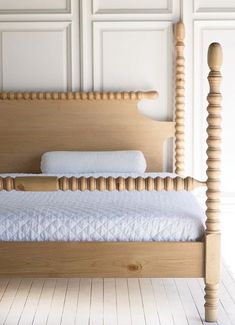 a wooden bed with white sheets and pillows