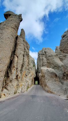 the road is surrounded by large rocks on both sides and has a tunnel between them