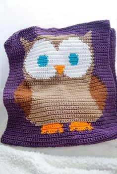 a crocheted owl pillow sitting on top of a white blanket