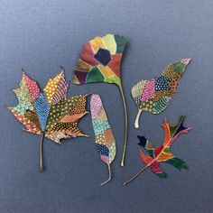 three different colored leaves on a blue surface with one being painted multicolored and the other is made out of metal