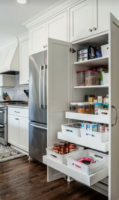 a kitchen with white cabinets and drawers filled with food