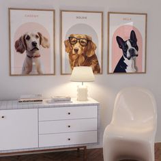 three dogs are hanging on the wall next to a white sideboard with a lamp