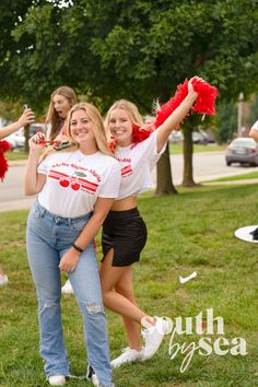 two girls in red and white cheerleader shirts posing for the camera with their arms up