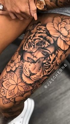 a woman's leg with a tiger and flowers tattoo on it