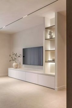 an empty living room with a large flat screen tv on the wall and shelves in front of it