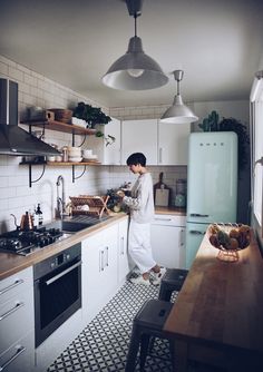 a woman standing in a kitchen next to a stove top oven and refrigerator freezer