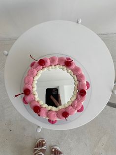 a cake with pink icing and cherries in the shape of a heart on a white plate