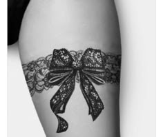 a black and white photo of a woman's thigh with a lace garter