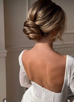 the back of a woman's head with her hair in a low bun, wearing a white dress