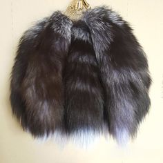 a black and grey fur coat hanging on a wall next to a gold brooch