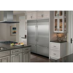 a stainless steel refrigerator in a kitchen with white cabinets and gray counter tops on the island