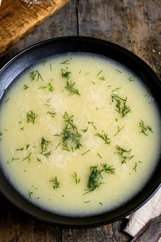 a black bowl filled with soup on top of a wooden table