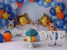 a cupcake with blue frosting sitting in front of balloons