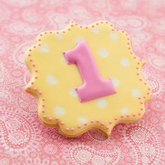 a decorated cookie with the number one on it sitting on a doily tablecloth