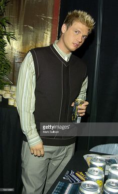 a young man standing next to a table with cans on it and looking at the camera