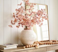 a vase filled with pink flowers sitting on top of a table next to a mirror