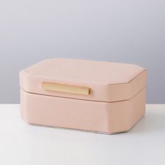 a small pink box with a gold handle on a white countertop next to a gray wall