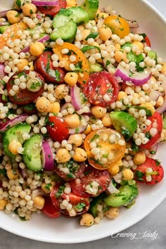 a white bowl filled with corn, tomatoes and cucumber on top of a table