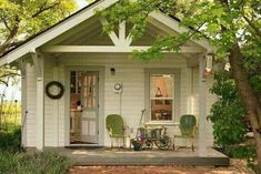 a small white house with two chairs and a bicycle on the porch