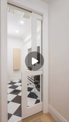 an open door in a white room with black and white checkerboard flooring