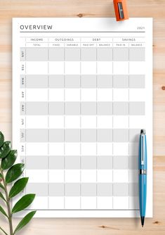 a printable planner with a pen on top of it and a plant next to it