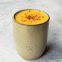 a cup filled with orange liquid sitting on top of a counter next to a napkin