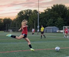 a woman kicking a soccer ball on top of a field