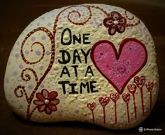 a painted rock that says one day at a time