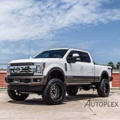 a white truck parked on top of a parking lot next to a red brick wall