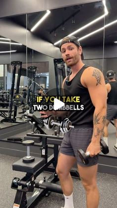 a man standing in front of a gym machine holding a dumbble bar and looking at the camera