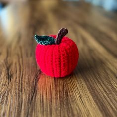 a crocheted apple sitting on top of a wooden table