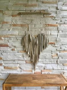 a wooden table sitting in front of a brick wall with driftwood hanging from it