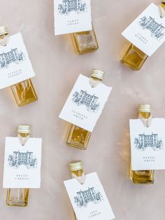 six small bottles of honey sitting on top of a table next to each other with tags hanging from them