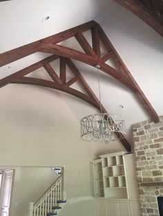 a chandelier hanging from the ceiling in a room with exposed beams and brick walls