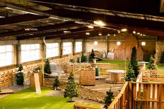 an indoor play area with artificial grass and wooden benches in the center, surrounded by trees