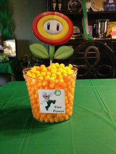 a cup filled with candy sitting on top of a table next to a green tablecloth