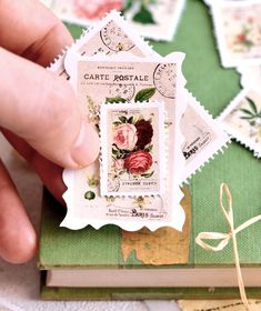 a hand holding a stamp with flowers on it and some other stamps in the background